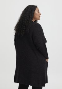 Lång, mörkgrå cardigan i texturerad stickad tyg, med sänkt axlar och sidofickor, med en avslappnad silhuett och rundad nederkant.