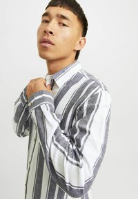 Camicia a righe in tonalità di blu e bianco, con maniche lunghe, colletto e una vestibilità rilassata in tessuto testurizzato.