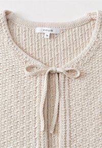 Pull en tricot couleur crème avec motif texturé, encolure ronde et nœud noué à l'avant, taille 36 de la marque OPUS.
