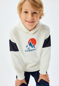 Felpa bianca con maniche navy, caratterizzata da una grafica montana e la scritta "DOWNHILL" in blu. Tessuto liscio con polsini a costine, vestibilità casual.