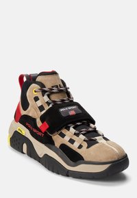 Chunky beige, black, and red sneaker with "Polo Sport" logo, thick sole, multi-colored laces, and a red heel pull tab.