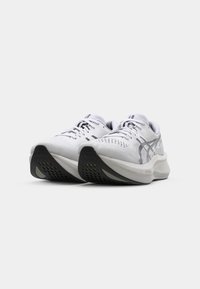 White athletic shoes with mesh upper, textured design, black rubber outsole, and reflective accents. Laces are threaded through eyelets.