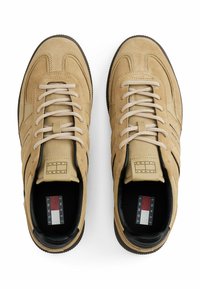 Khaki-suede Sneakers mit hellbeige Akzenten, runden Schnürsenkeln und einer schwarzen Gummisohle. Merkmal ist ein Logo-Tag auf der Zunge und eine gemusterte Innensohle.