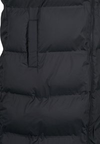 Mustat puffer-liivit, joissa on tikatut osat, varustettu vetoketjulla ja tasaisella taskulla edessä. Silky, kevyt materiaali.