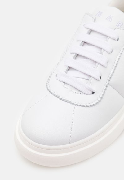 Weißes Leder-Sneaker mit gesteppten Details, flachen Schnürsenkeln und einer strukturierten Sohle. Verfügt über eine runde Zehenpartie und ein minimalistisches Design.