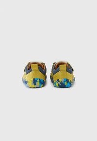 Chaussures pour enfants jaunes et bleues en suède et mesh, avec une doublure rembourrée et une semelle multicolore à motif tie-dye.