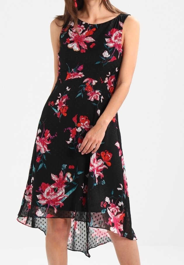 Czarna sukienka w kwiaty z bezrękawowym fasonem, z czerwonymi i białymi kwiatami, o asymetrycznym niższym kroju i akcentami w kropki na dole.