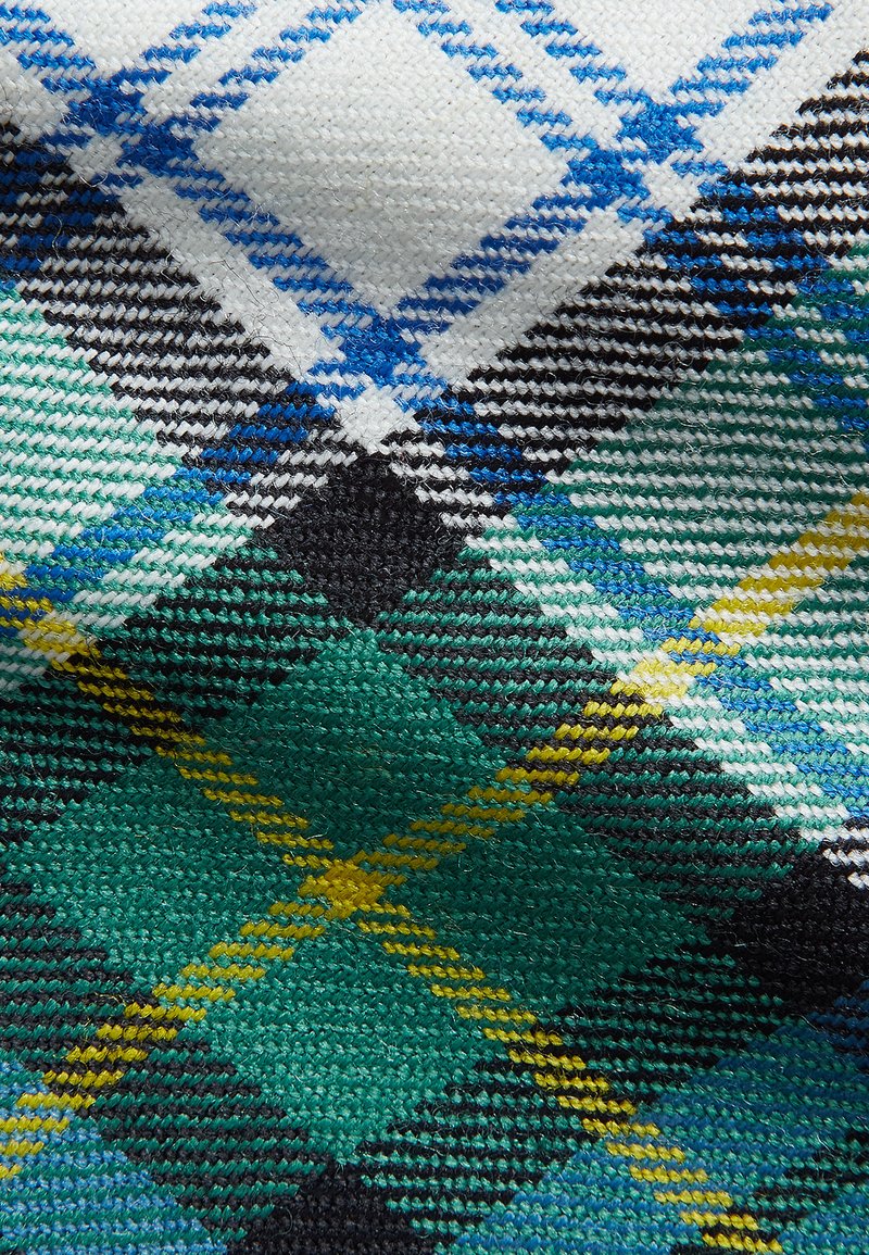 Tartan textile featuring a pattern of blue, green, black, and yellow diamonds on a white background, with a woven texture.
