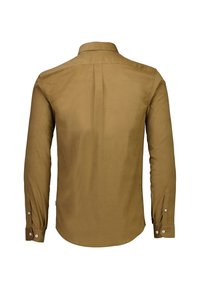 Camicia con bottoni di colore beige, realizzata in tessuto morbido, con colletto, maniche lunghe e polsini con bottoni, rifinita con un orlo curvo.