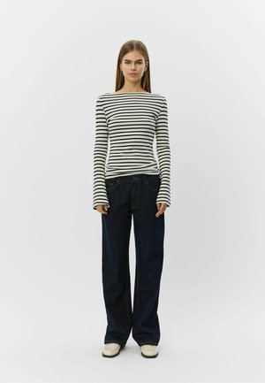 Triibuline must-valge pikkade varrukatega särk, kombineeritud laia säärega tume siniste teksadega. Komplekt on mugava lõikega ja koosneb igapäevastest kingadest.