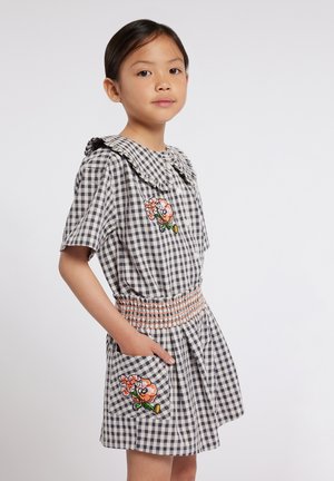 Robe vichy avec un col volanté, des manches courtes, une taille élastique, des poches latérales et une broderie florale sur la poitrine et la poche.