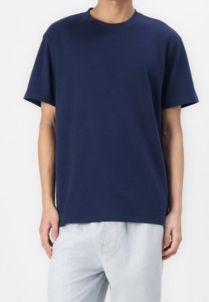 Donkerblauw katoenen T-shirt met een losse pasvorm, ronde hals, korte mouwen en een gladde textuur. Gecombineerd met lichtgekleurde broek.