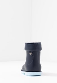 Botte en caoutchouc imperméable bleu marine avec un col retroussé, semelle bleu clair et logo « igor » sur le côté. Design simple avec une texture lisse.