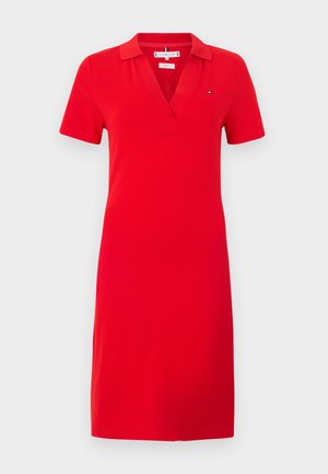 Vestito polo rosso in tessuto liscio, con scollo a V e maniche corte. Presenta un piccolo dettaglio logo sul lato sinistro del petto.