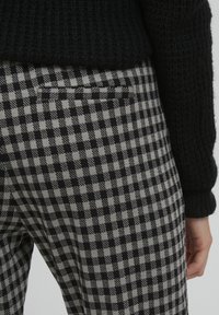 Zwart en grijs geblokte broek met een gemêleerde gebreide tailleband, voorzien van een discreet achterzakje en een slanke, op maat gemaakte pasvorm.