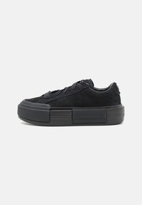 Adidași din suede negru cu șireturi plate, o talpă groasă din cauciuc și un element de design în formă de bloc rectangular pe mijlocul tălpii.