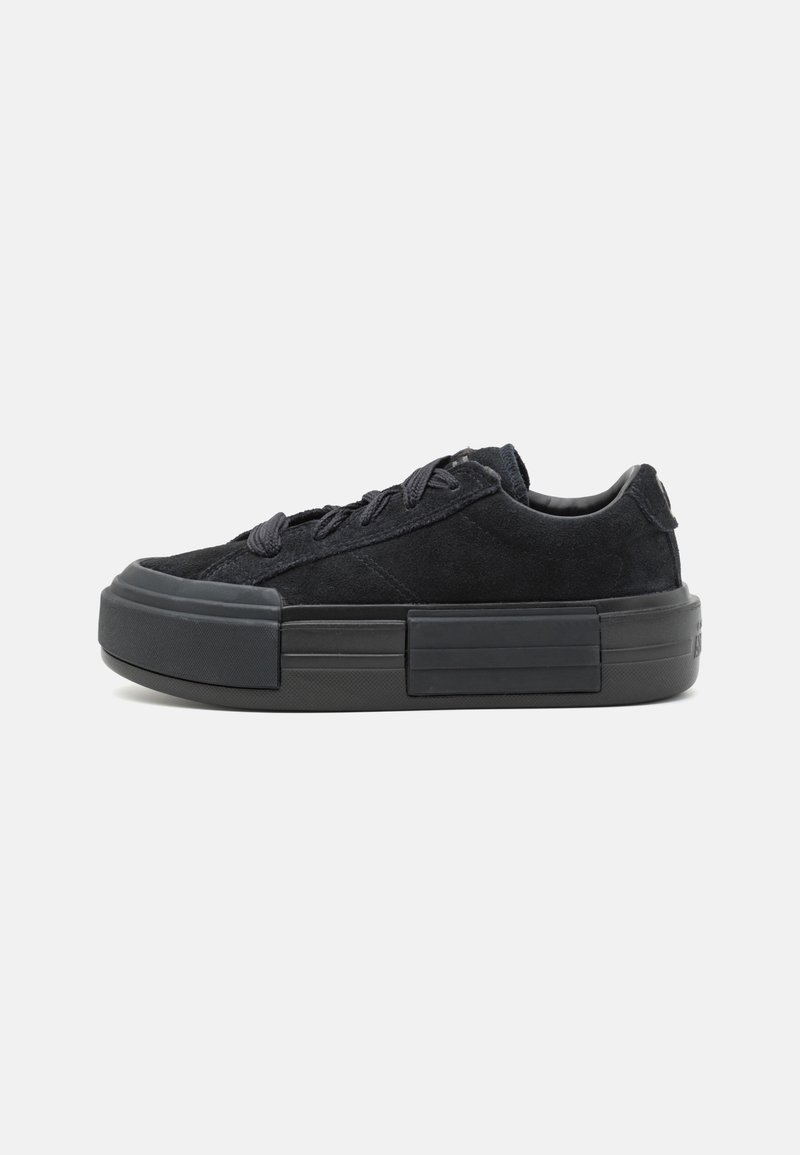 Adidași din suede negru cu șireturi plate, o talpă groasă din cauciuc și un element de design în formă de bloc rectangular pe mijlocul tălpii.