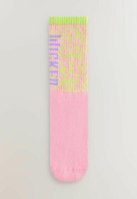 Rosa strumpor med ett texturerat mönster och gröna detaljer upptill, med ordet "Wicked" i lila. Mjuk material, midikalvlängd.