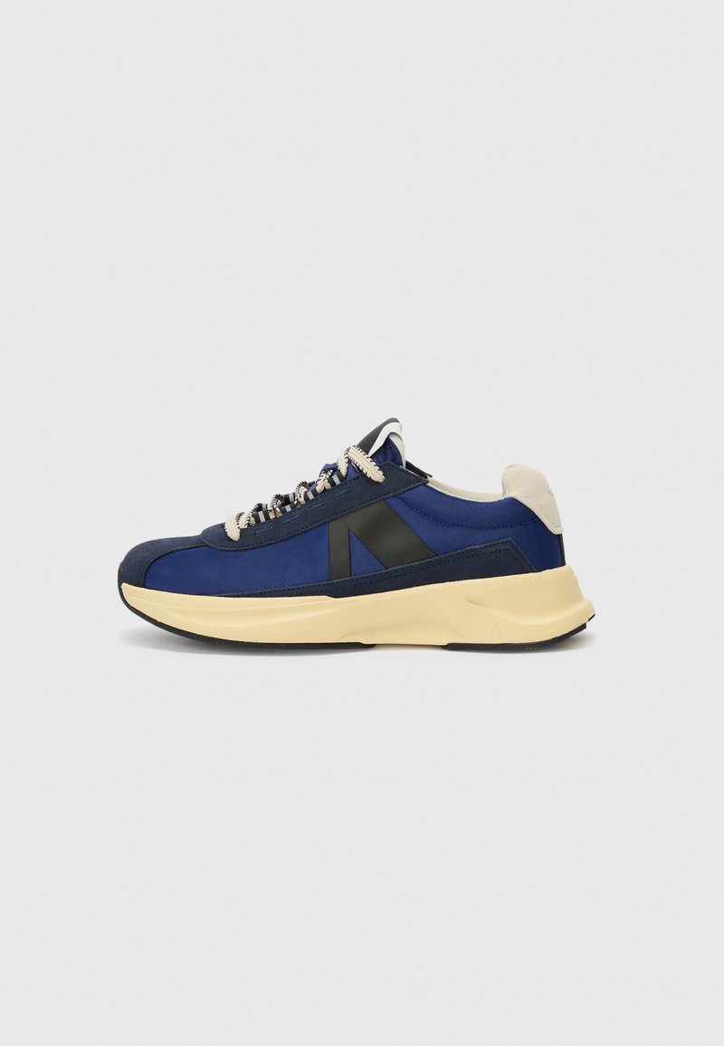 Sport shoes in navy blue fabric with a black accent, light beige sole, textured surface, and contrasting laces.