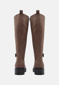 Braune kniehohe Stiefel aus glattem Material, mit einem Reißverschluss, einem Zugtab hinten und einer stabilen schwarzen profilierten Sohle.