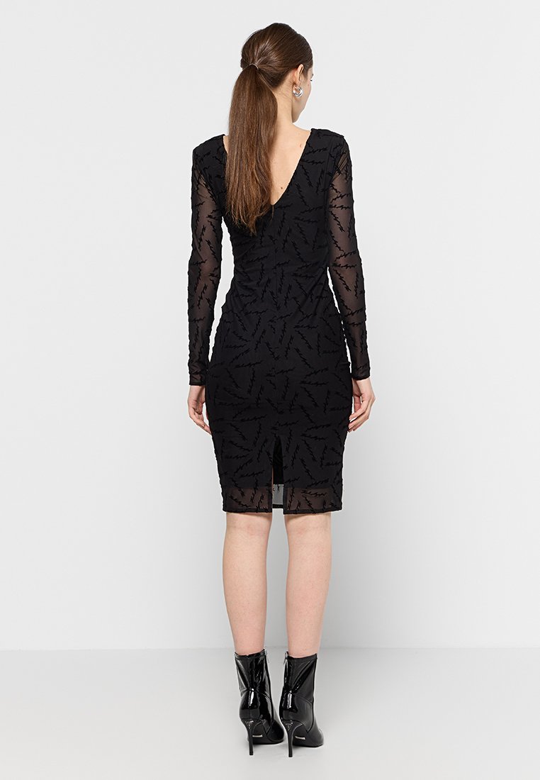 Vestido negro con mangas largas transparentes, un escote en V en la parte posterior y una abertura en el frente. Presenta un patrón texturizado que recuerda a hojas en la tela.