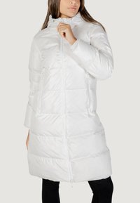 Cappotto lungo bianco e gonfio con colletto alto, design trapuntato, due tasche laterali e zip frontale, realizzato in un tessuto liscio e lucido.