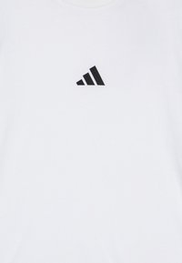 Camiseta blanca de algodón con un gráfico negro de tres rayas diagonales en el frente. Cuello redondo y mangas cortas.
