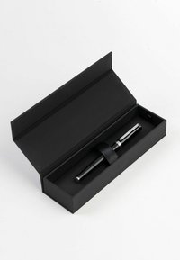 Stylo noir dans un élégant coffret noir, présentant un design épuré, des accents métalliques brillants et un ruban satin pour maintenir le stylo en place.