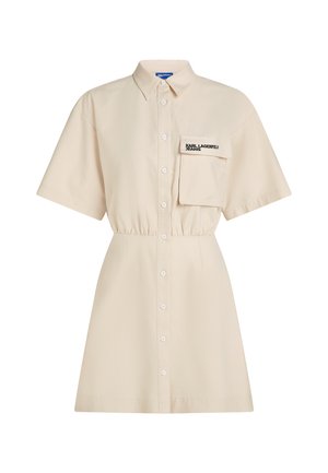 Béžové šaty košilového střihu s krátkými rukávy, zapínáním na knoflíky vpředu, klopovou náprsní kapsou označenou nápisem "KARL LAGERFELD JEANS" a staženým pasem.