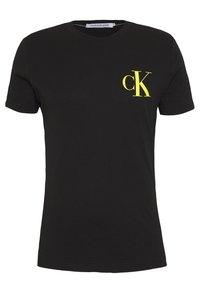 Černé bavlněné tričko s krátkým rukávem, které má na levé straně hrudi žluté logo "CK". Klasický design s kulatým výstřihem.