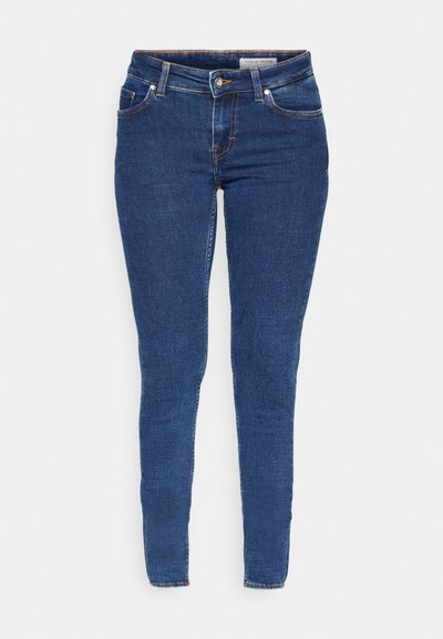 Tykke jeans laget av mørkeblå denim, med fem lommer, beltehemper og oransje søm langs sømmene. Glatt tekstur og tettsittende design.