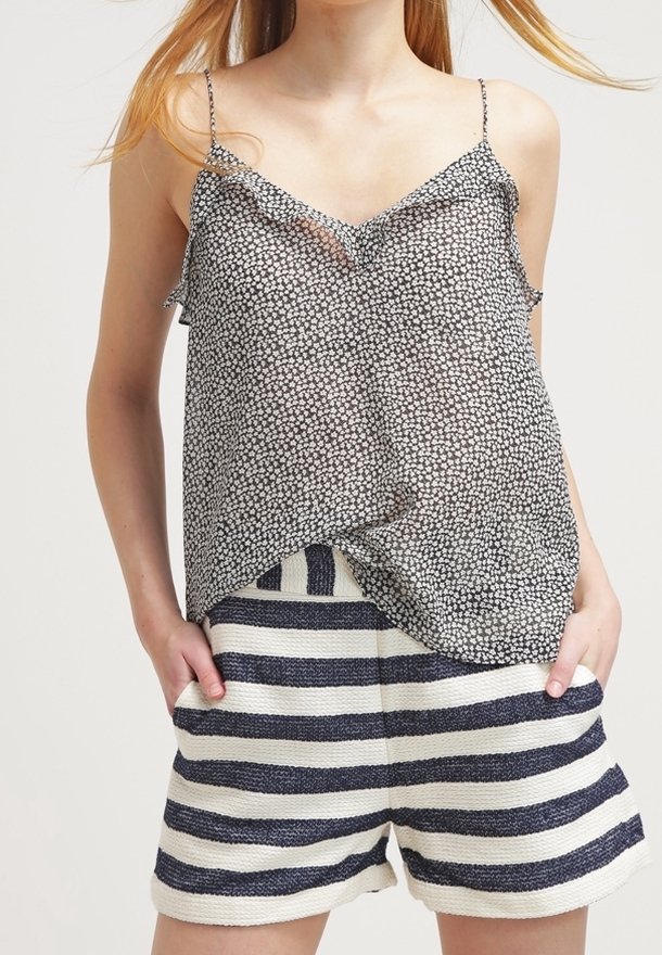 Mustavalkoinen kukkakuosiset toppi ohuilla olkaimilla, yhdistettynä kermanvärisiin ja tummansinisiksi raidoitettuihin shortseihin, joissa on teksturoitu kangas.