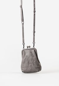 Borsa in pelle grigia con forma rotonda, chiusura a scatto e tracolla regolabile. Presenta una texture liscia e un design minimalista.