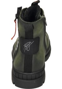 Botín de tobillo verde oliva con un acabado de cuero suave, acentos en negro contrastantes, cierre de cremallera y suela de goma texturizada. Detalle característico en la parte posterior.