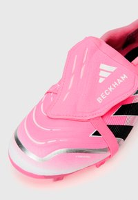 Chuteira de futebol rosa com um cabedal texturizado, apresentando riscas pretas, detalhes refletivos em prata e uma faixa de velcro rotulada "BECKHAM."