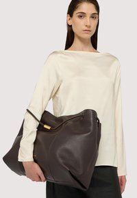 Braune Leder-Shopper-Tasche mit weicher Textur, großem Format und einem einzelnen Griff. Goldfarbene Hardware-Akzentuierung am Tascheneingang.