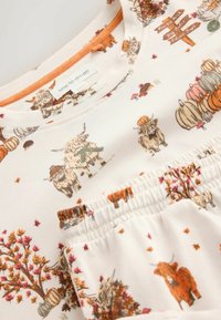 Soft white fabric with autumn-themed print including pumpkins, trees, highland cows, and a wooden sign with seasonal text.