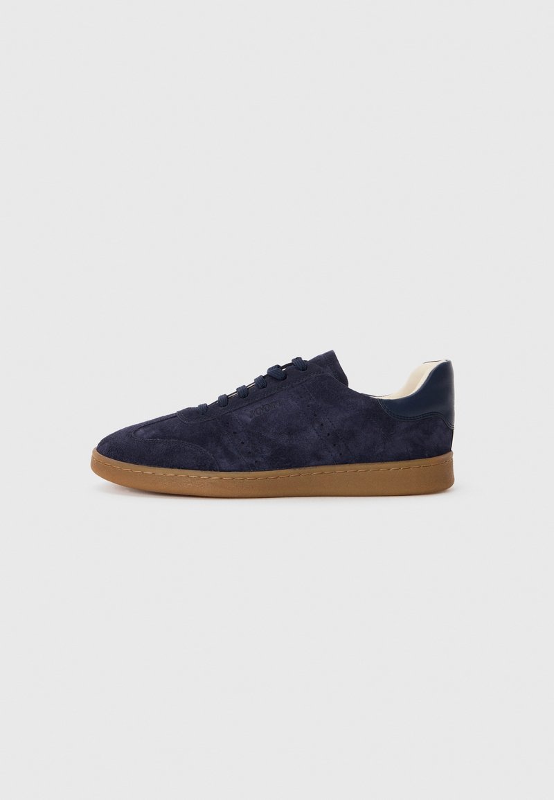 Tengerészeti velúr sneaker, gumi talppal, kerek orral és tengerészeti kiegészítőkkel. Jellemzője a tonális fűző és a perforált részletek az oldalakon.