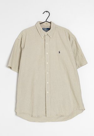 Beżowa koszula w kratę z krótkim rękawem, zapinana na guziki, z kołnierzykiem i logo Polo Ralph Lauren na piersi, wisząca na czarnym wieszaku.