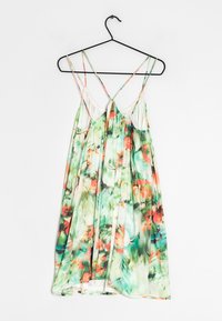 Vestido sin mangas floral en tela liviana, con un patrón en verde y naranja, tirantes delicados y un diseño holgado.