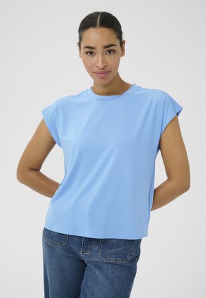 Haut bleu clair à manches courtes en tissu lisse. Présente un col rond et une coupe ample, associé à un jean bleu foncé dans un style décontracté.