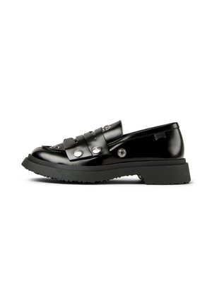 Mocassin en cuir noir brillant avec semelle en caoutchouc épaisse, détails à clous argentés, et une bride sur le dessus, présenté sur un fond blanc.