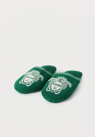 Πράσινα βαμβακερά παντόφλες με κεντημένα λευκά σχέδια κεφαλής Μέδουσας στην πάνω πλευρά, εμφανιζόμενες σε λευκό φόντο.
