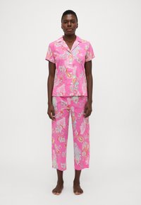 Rozā pidžamu komplekts ar paisley rakstu; īsu piedurkņu pogājama krekla augšdaļa un brīvi pieguļošas bikses. Izgatavots no viegla auduma ar smalku spīdumu.