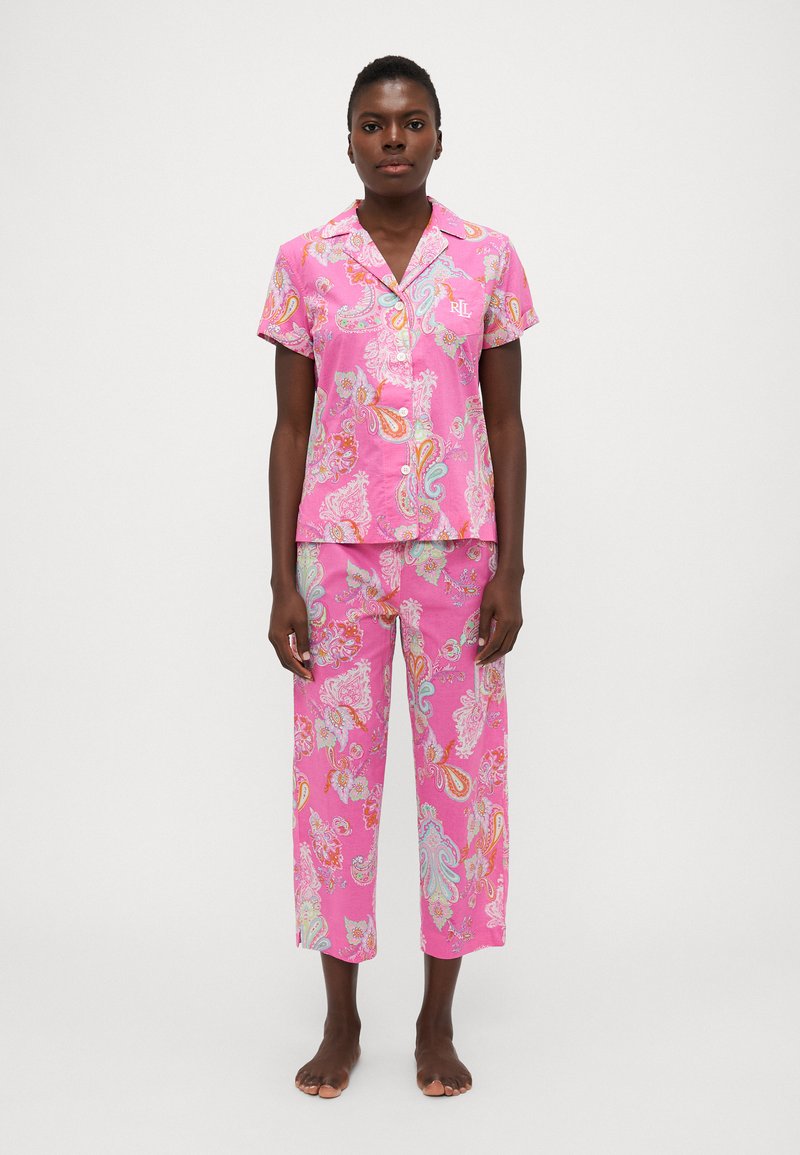 Rozā pidžamu komplekts ar paisley rakstu; īsu piedurkņu pogājama krekla augšdaļa un brīvi pieguļošas bikses. Izgatavots no viegla auduma ar smalku spīdumu.