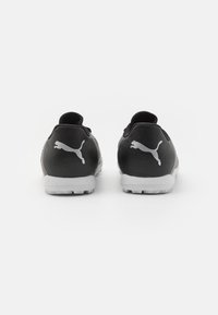 Scarpe sportive nere con tomaia texturizzata, collo imbottito, suola in gomma grigia e logo Puma prominently visibile sul tallone.