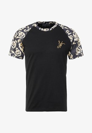 T-shirt noir à manches courtes avec tissu imprimé beige et marine sur les manches. Présente un logo doré sur la poitrine et un col rond.