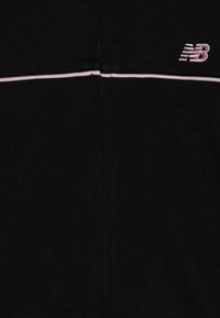 Czarna kurtka typu zip-up z miękkiego materiału, z jasnoróżowym akcentem w postaci paska oraz subtelnym haftowanym logo "NB" po lewej stronie u góry.