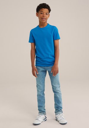 Blå t-shirt med kort ärm i bomull, kombinerad med ljusblå jeans och vita sneakers, med rund halsringning och avslappnad passform.