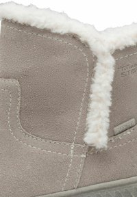 Grijze suède enkelboot met een fluffy witte voering en gestikte details. Voorzien van een gestructureerde zool en een klein merklabel met de tekst "DUO-TEX."